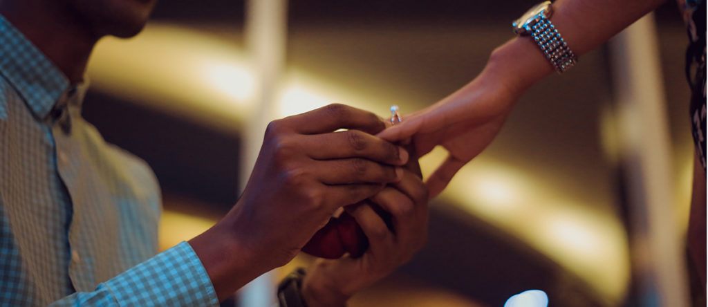 Gentleman on one knee putting a ring on his fiancée outdoors | Marriage Law in Kenya | Njaga & Co. Advocates family law firm in Kenya