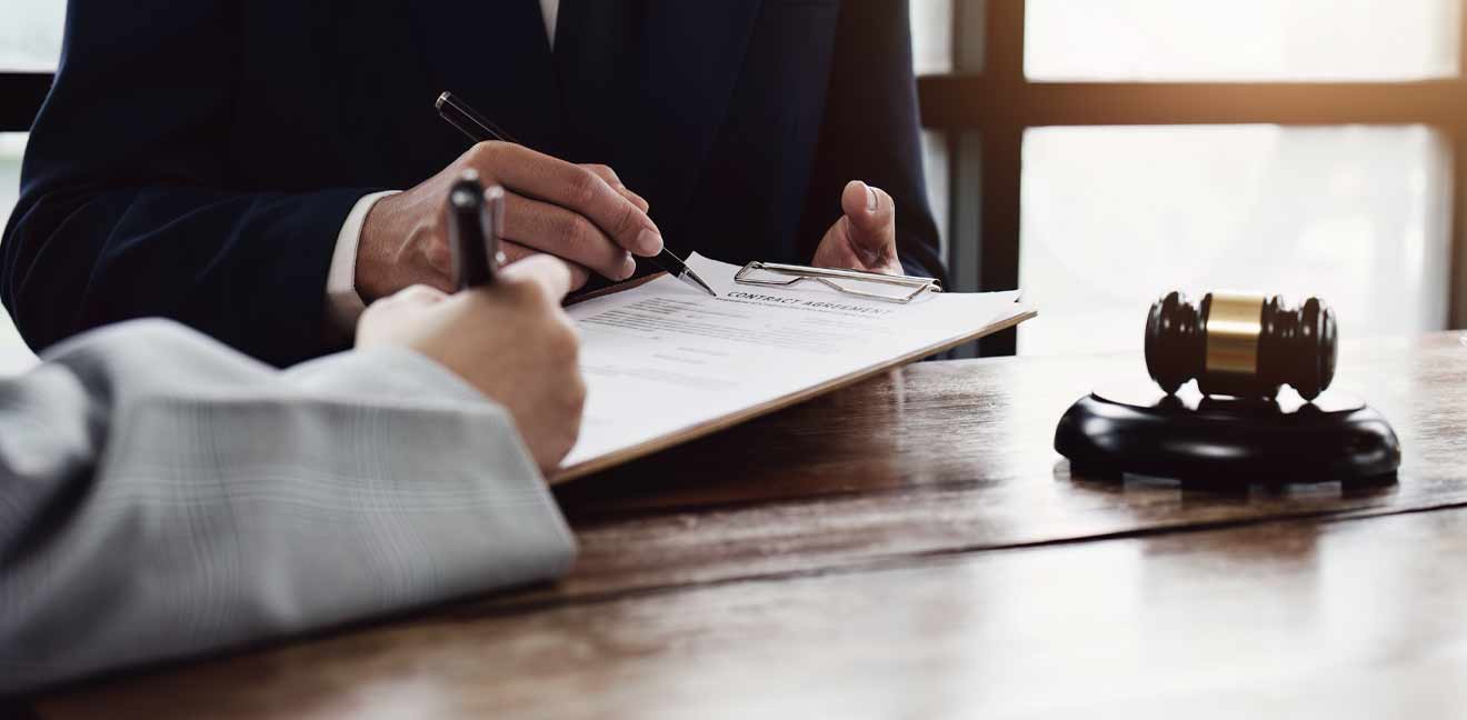 Lawyer showing client where to sign document with a gavel next to them