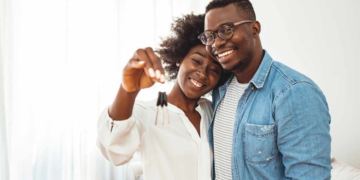 Couple all smiles hugging as the lady holds a key inside a house | Co-owning Property in Kenya | Njaga Advocates property law