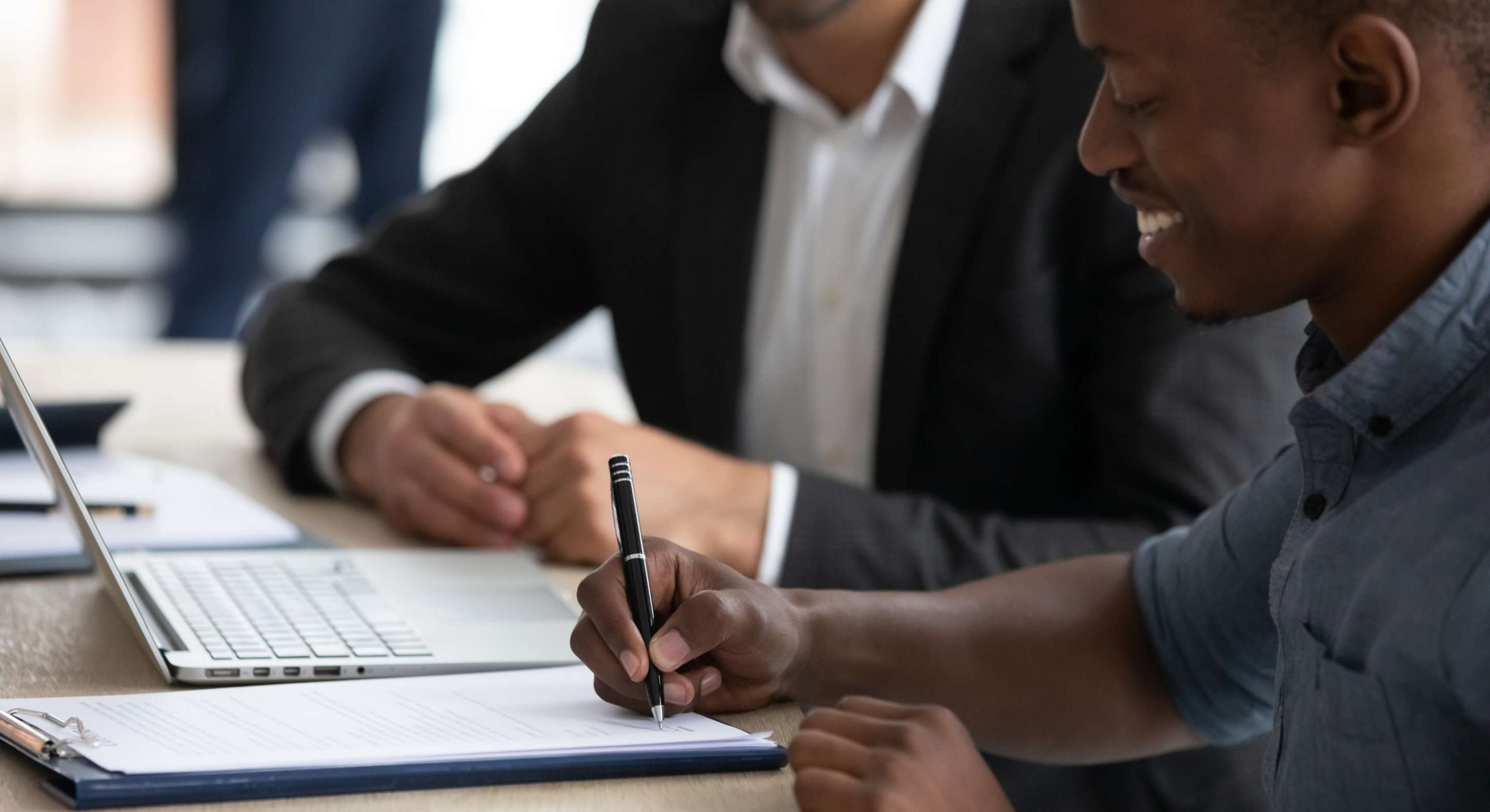 Gentleman signing contract all smiles next to his lawyer | The Importance of Written Contracts in Business and Tips for Negotiating Commercial Contracts in Kenya | Njaga & Co. Advocates commercial lawyers