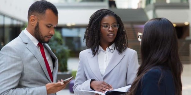 A group of three people professionally dressed discussing outdoors while standing | Beneficial Ownership in Kenya | Njaga Advocates Corporate & Commercial legal articles