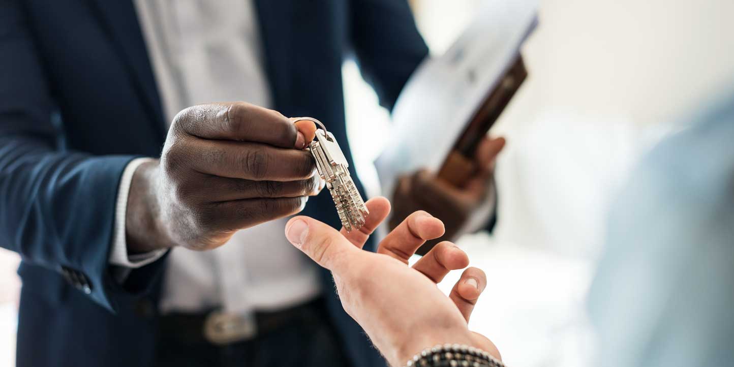 Real-estate-conveyancing A professional handing over a house key to another person, symbolizing real estate transactions and property conveyancing | Legislative Framework Governing Real Estate Conveyancing in Kenya | Njaga & Co. Advocates legal articles