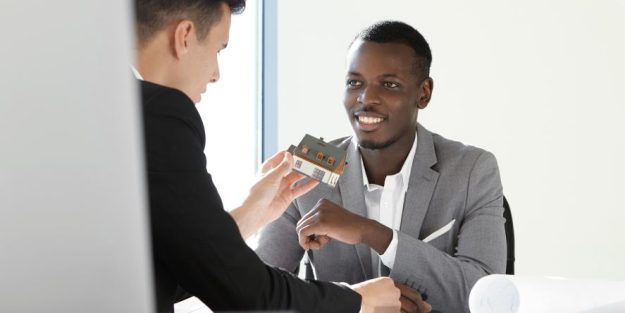 An advocate and a client discussing property purchase; the advocate is holding a small house model | The Role of an Advocate in Property Purchase in Kenya | Njaga Advocates article about law