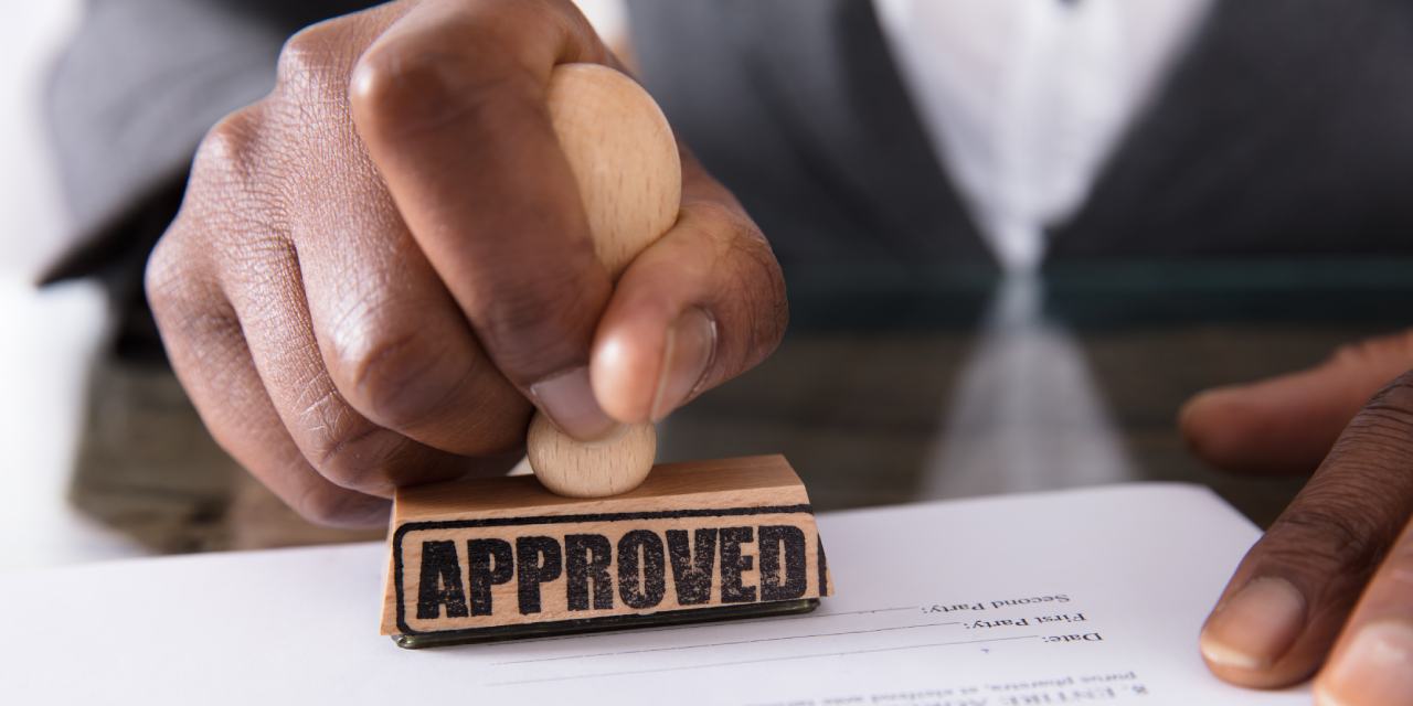 Hand with approved stamp on document | Comprehensive Guide to Class G (Investor) Permit in Kenya | Njaga & Co. Advocates immigration lawyer