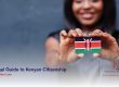An African descent lady holding a mini Kenyan flag forward all smiles | Legal Guide to Kenyan Citizenship | 22 FAQs answered on how to become a citizen of kenya